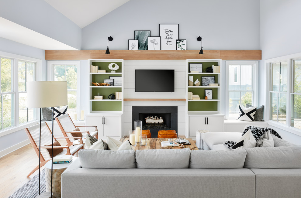 Idée de décoration pour un salon marin avec un mur bleu, un sol en bois brun, une cheminée standard, un téléviseur fixé au mur et un sol marron.