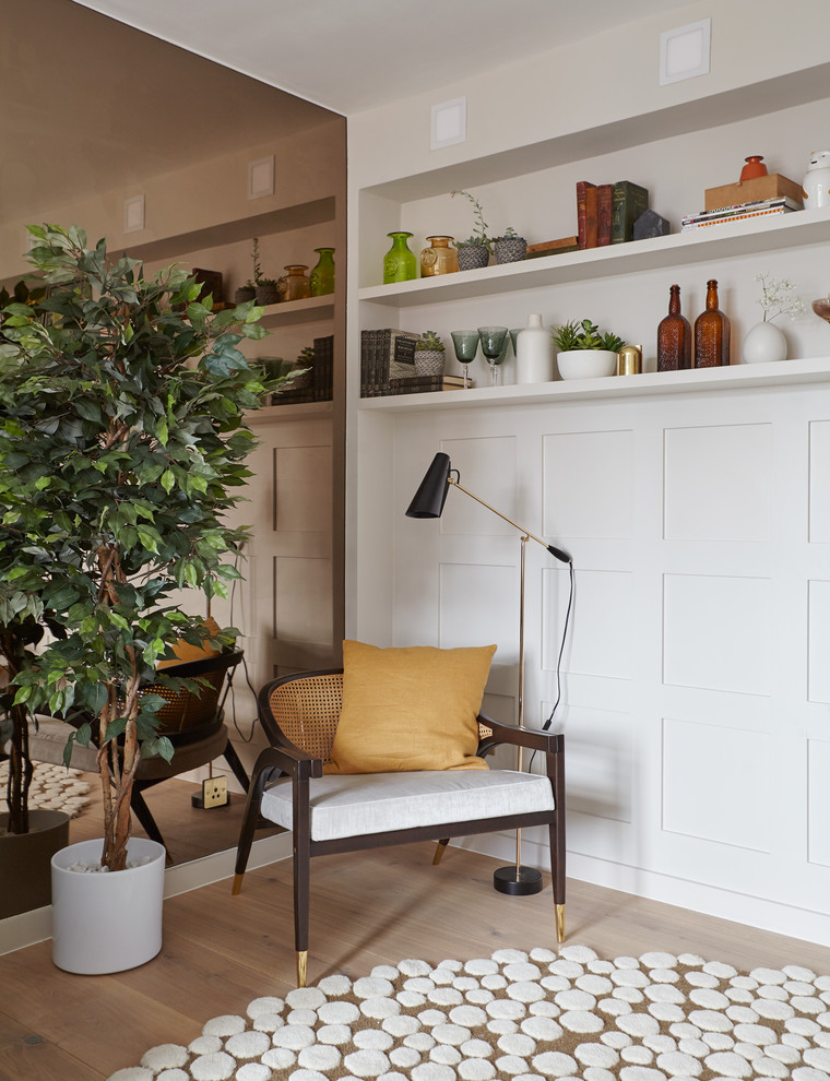 Example of a small mid-century modern enclosed medium tone wood floor living room design in London with white walls