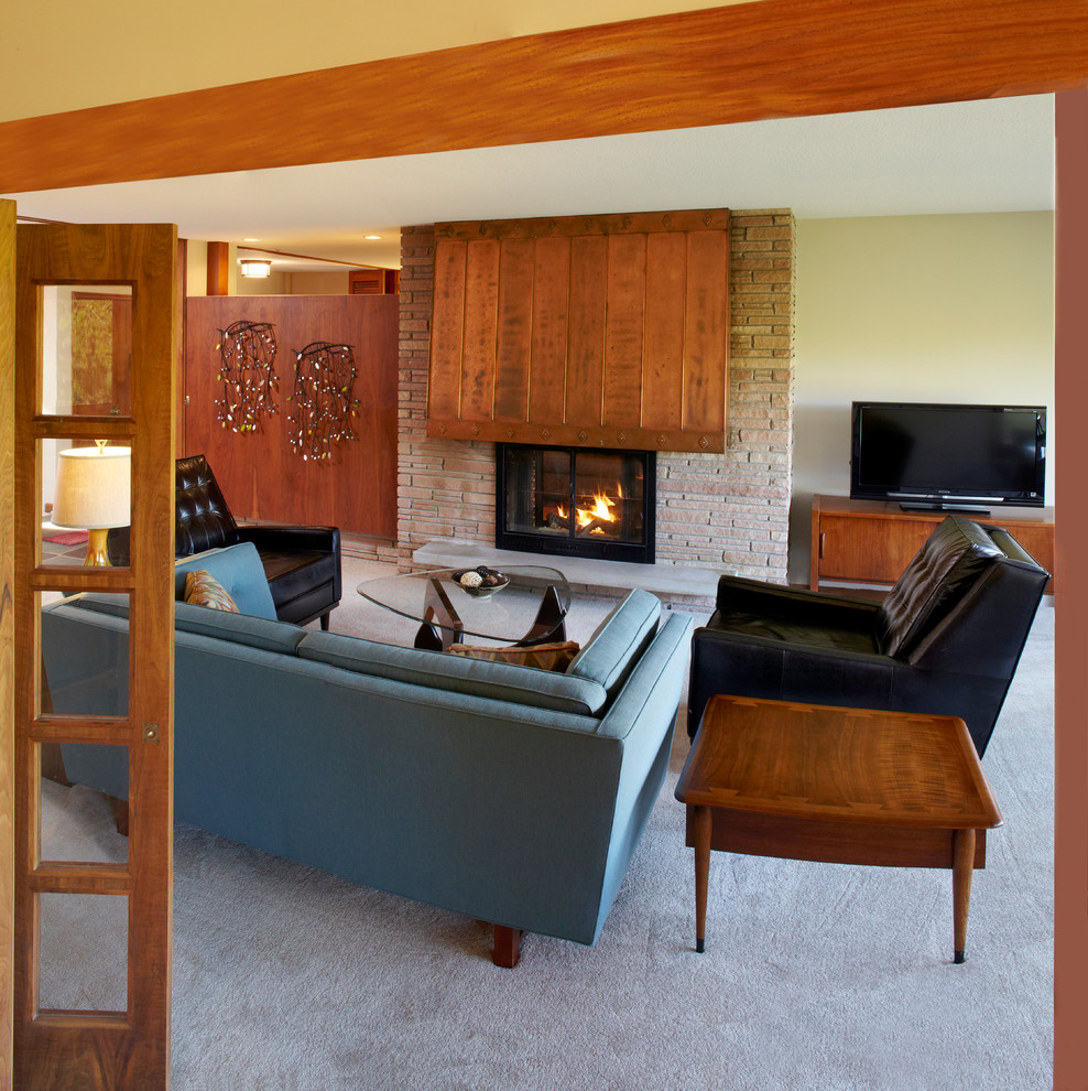 Retro living room in Minneapolis with beige walls, carpet, a two-sided fireplace and a brick fireplace surround.