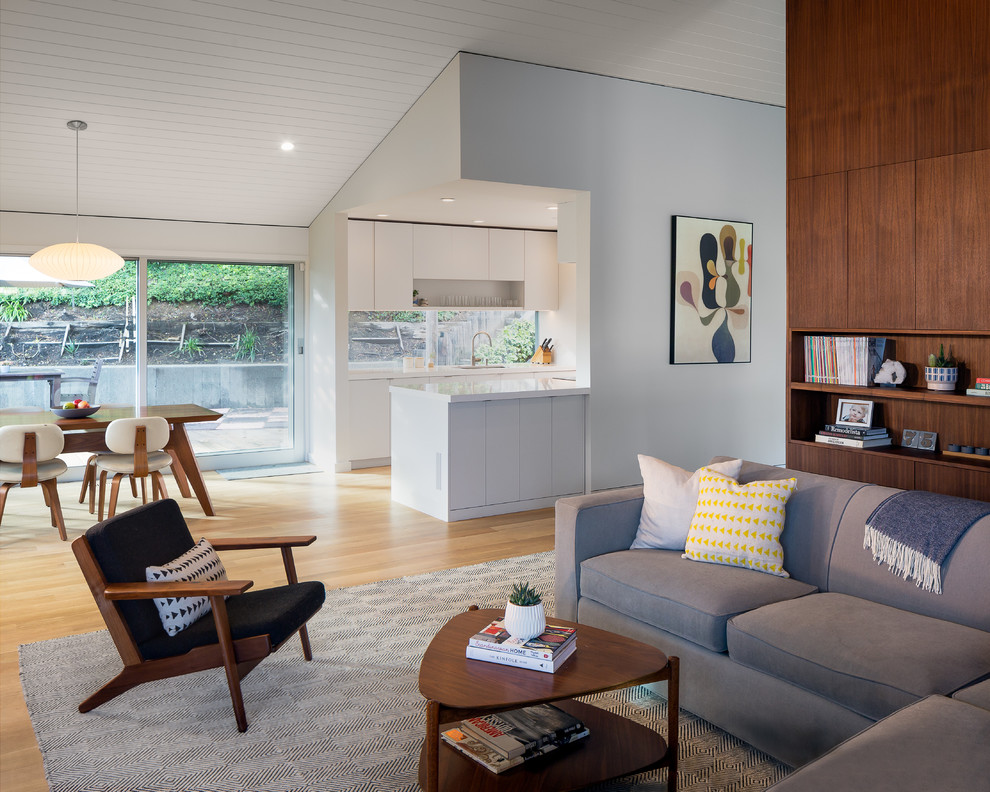 Esempio di un grande soggiorno minimalista aperto con pareti bianche, parquet chiaro e pavimento beige