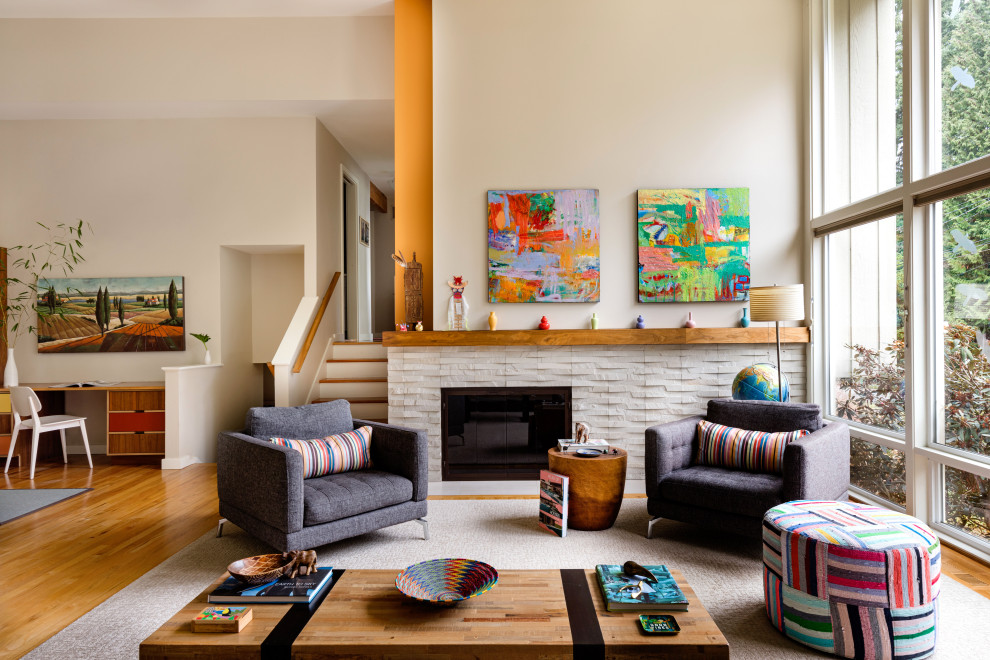Mittelgroßes, Fernseherloses, Offenes Modernes Wohnzimmer mit braunem Holzboden, Kamin, Kaminumrandung aus Stein, beiger Wandfarbe und braunem Boden in Seattle