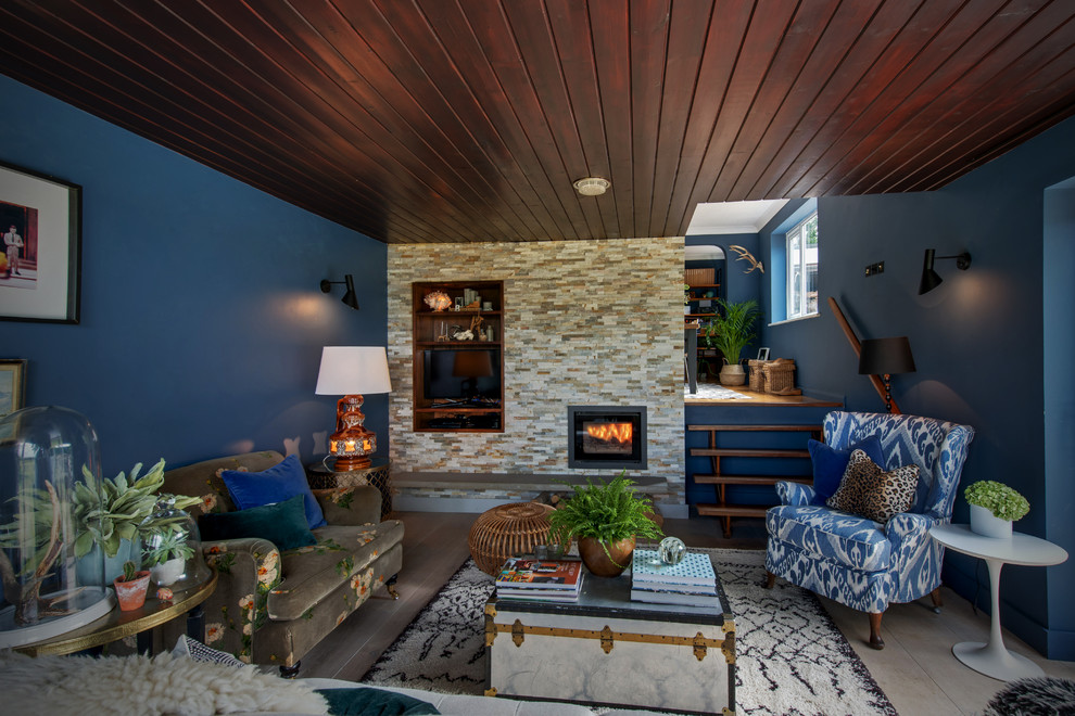 Diseño de salón ecléctico de tamaño medio con paredes azules, suelo de madera clara, todas las chimeneas y marco de chimenea de ladrillo