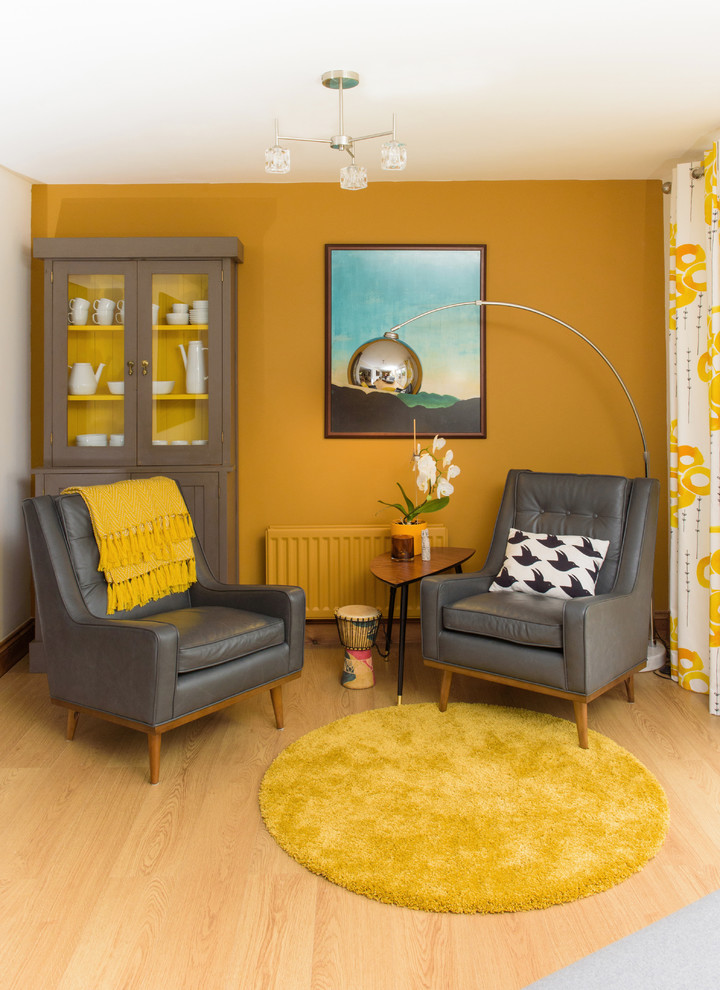 Modelo de biblioteca en casa abierta contemporánea de tamaño medio sin chimenea y televisor con paredes amarillas y suelo de madera en tonos medios