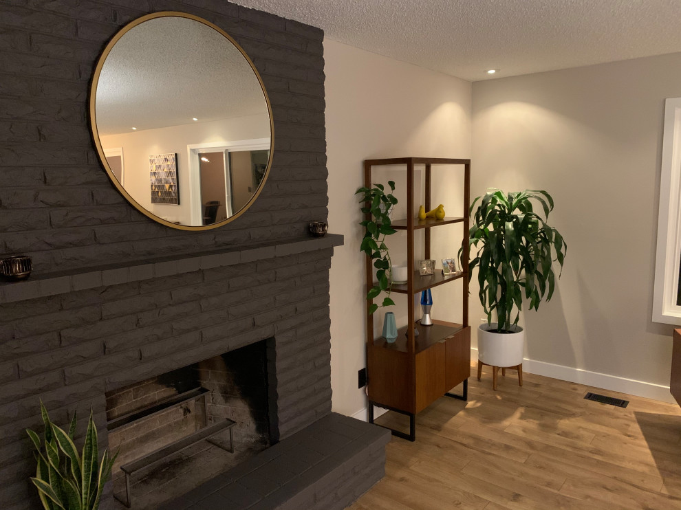Modelo de salón abierto retro de tamaño medio sin televisor con paredes grises, suelo de madera clara, todas las chimeneas, marco de chimenea de ladrillo y suelo beige