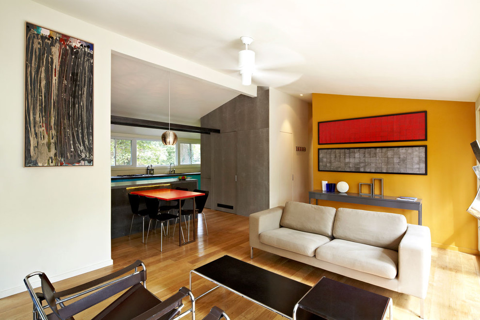 Imagen de salón retro con paredes amarillas y suelo de madera en tonos medios