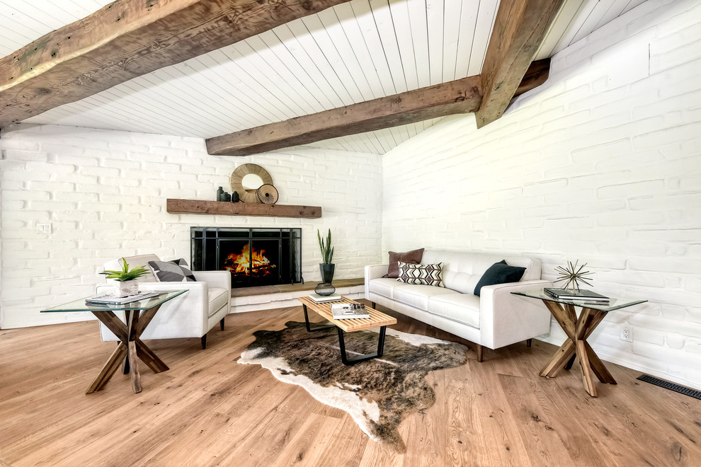 Aménagement d'un grand salon rétro ouvert avec un mur blanc, parquet clair, une cheminée standard, un manteau de cheminée en brique et un sol marron.