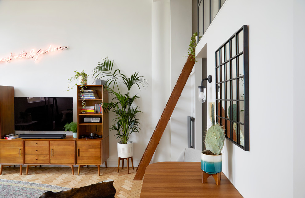 Mittelgroßes, Offenes Retro Wohnzimmer mit weißer Wandfarbe, hellem Holzboden, TV-Wand und braunem Boden in London