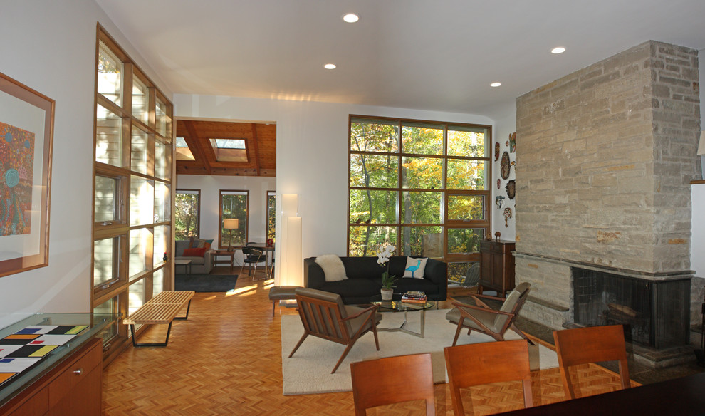 Idée de décoration pour un grand salon vintage ouvert avec un mur blanc, un sol en bois brun, une cheminée d'angle et un manteau de cheminée en pierre.