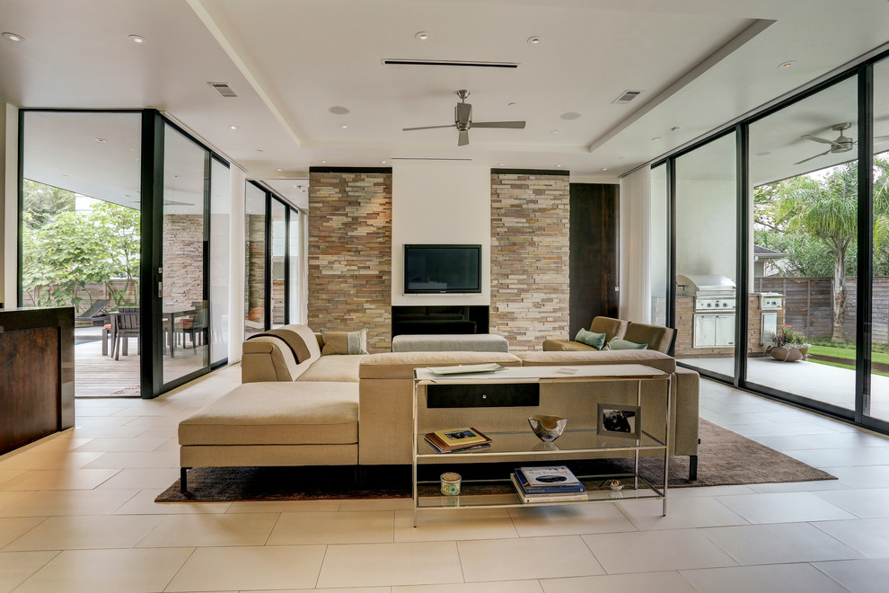 Cette image montre un salon design avec une cheminée standard, un manteau de cheminée en pierre et un téléviseur fixé au mur.