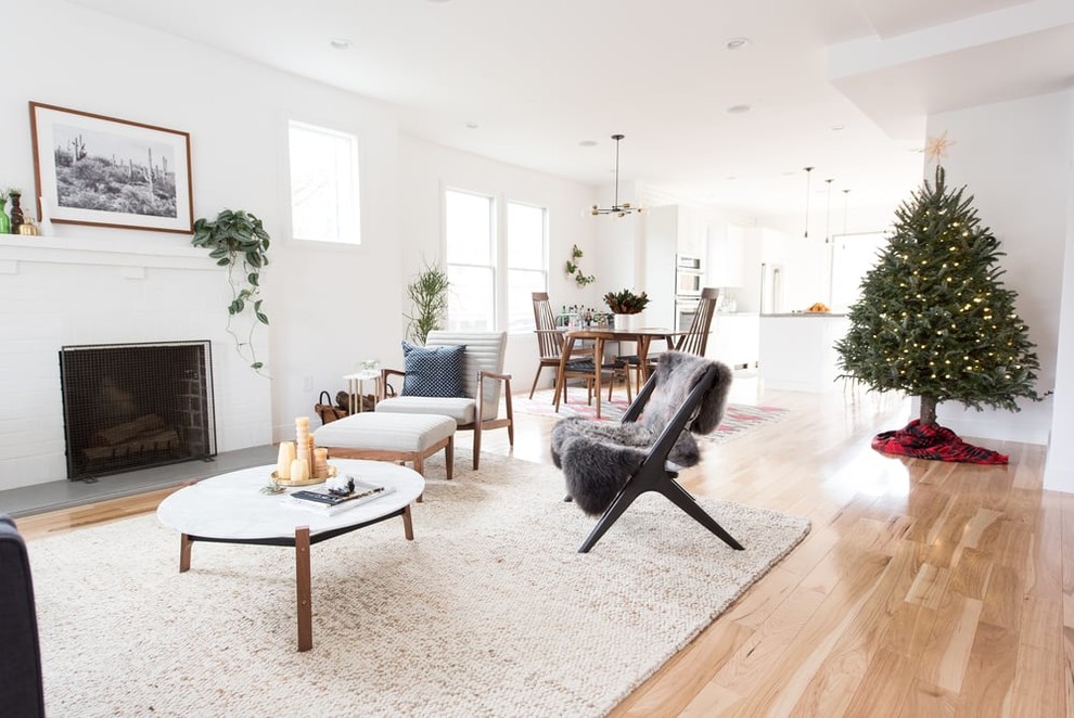Photo of a traditional open plan living room in DC Metro with white walls, light hardwood flooring, a standard fireplace, a tiled fireplace surround and brown floors.
