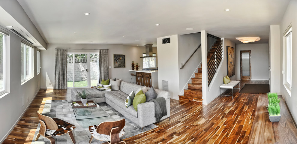 Mittelgroßes, Offenes, Repräsentatives, Fernseherloses Retro Wohnzimmer ohne Kamin mit grauer Wandfarbe, braunem Holzboden und braunem Boden in Los Angeles