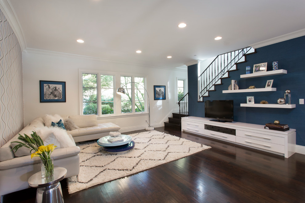 This is an example of a large contemporary mezzanine living room in Los Angeles with blue walls, dark hardwood flooring and a freestanding tv.