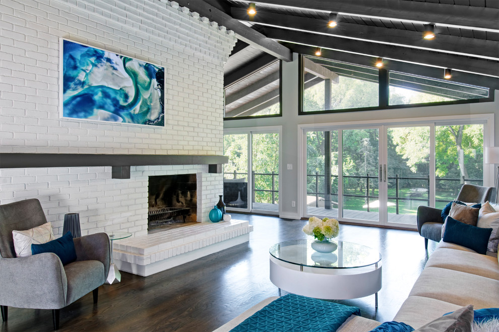 Example of a mid-sized mid-century modern open concept dark wood floor and brown floor living room design in Columbus with white walls, a brick fireplace and a standard fireplace