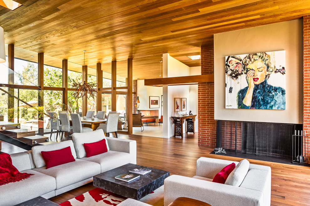 Cette photo montre un grand salon tendance ouvert avec une salle de réception, un sol en bois brun, une cheminée standard et un manteau de cheminée en brique.