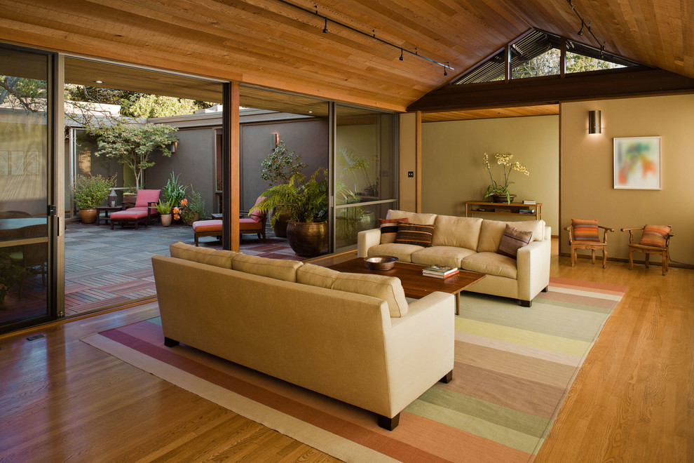 Inspiration pour un grand salon minimaliste ouvert avec un sol en bois brun et un mur beige.