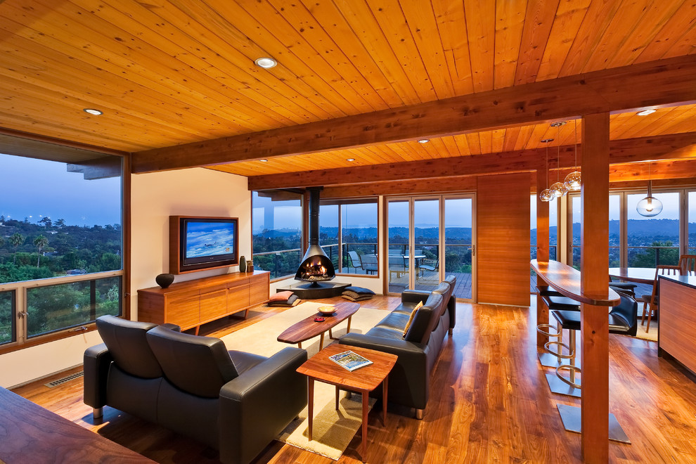 Photo of a retro formal open plan living room in Santa Barbara with medium hardwood flooring, a wall mounted tv and a hanging fireplace.