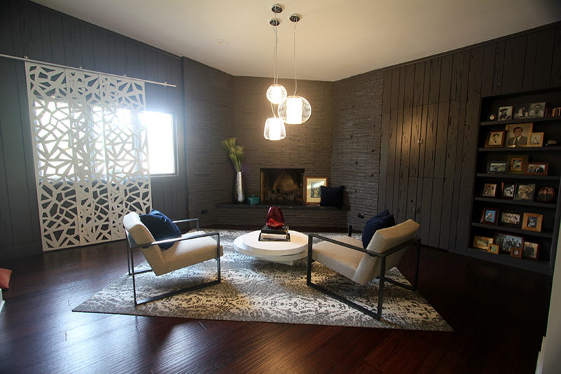Стильный дизайн: открытая гостиная комната среднего размера в стиле ретро с серыми стенами, темным паркетным полом, телевизором на стене, коричневым полом, стандартным камином и фасадом камина из камня - последний тренд