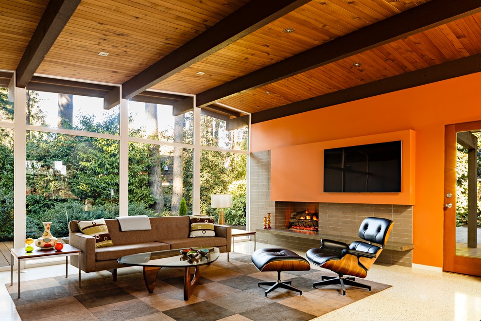 Modelo de salón abierto retro de tamaño medio con parades naranjas, televisor colgado en la pared, todas las chimeneas y marco de chimenea de ladrillo