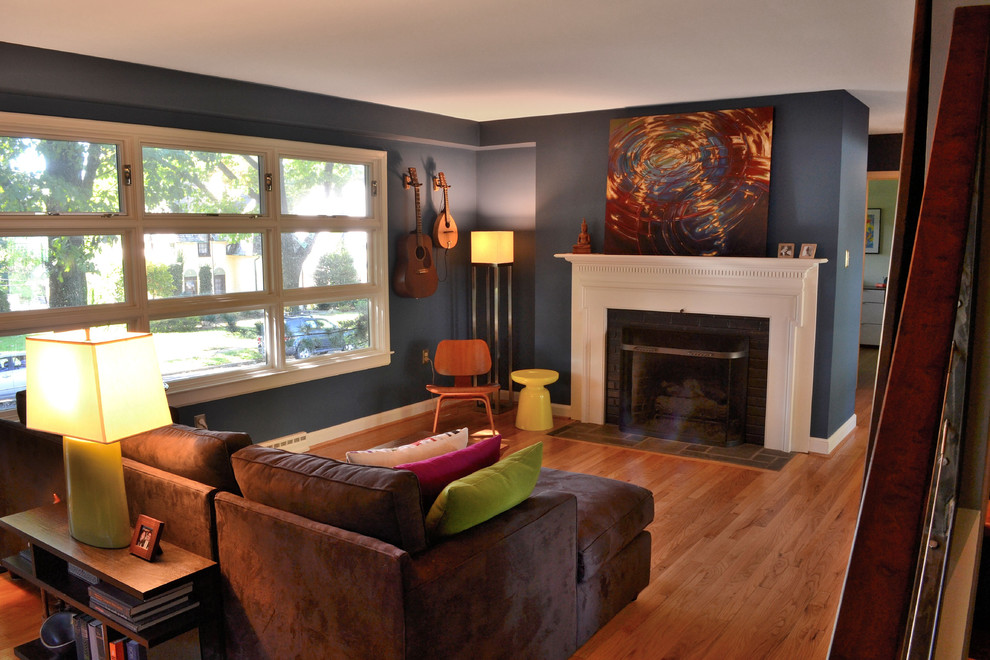 Immagine di un soggiorno moderno aperto con pareti blu, pavimento in legno massello medio, camino classico e cornice del camino in legno