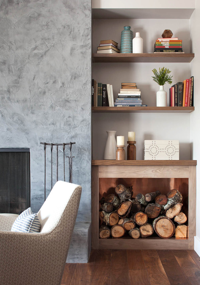 Cette photo montre un salon tendance avec un mur gris, parquet foncé, une cheminée standard et un manteau de cheminée en plâtre.