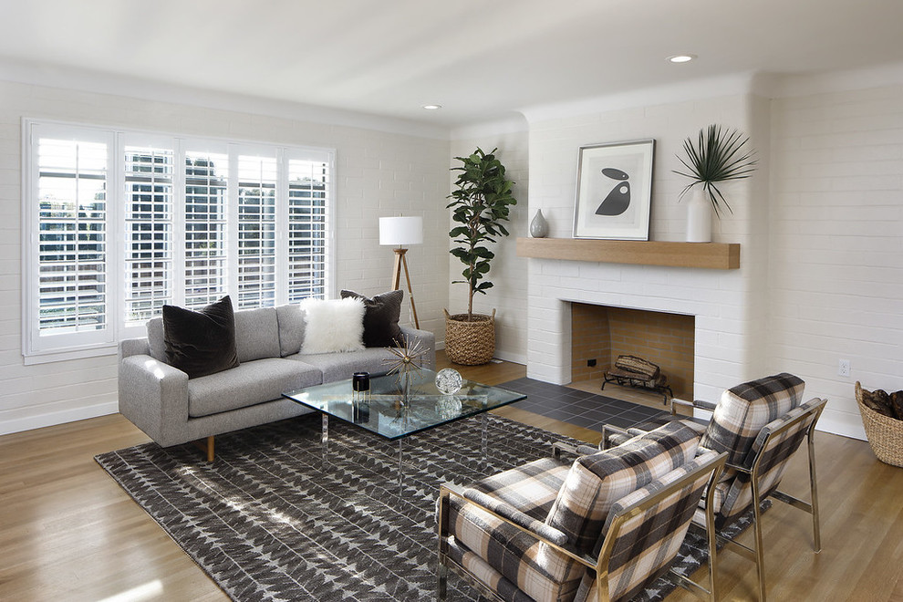 Inspiration for a traditional living room in San Francisco with white walls, medium hardwood flooring, a standard fireplace, a brick fireplace surround, brown floors and feature lighting.