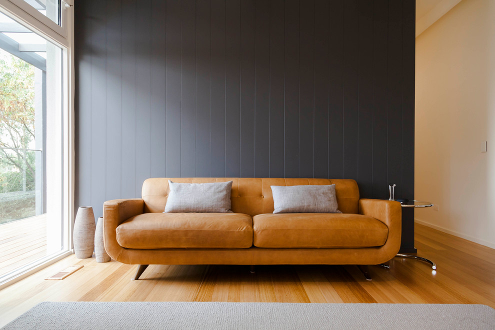 Idee per un grande soggiorno minimalista aperto con pareti blu, pavimento in legno massello medio, camino sospeso, cornice del camino in pietra, TV a parete e pavimento marrone