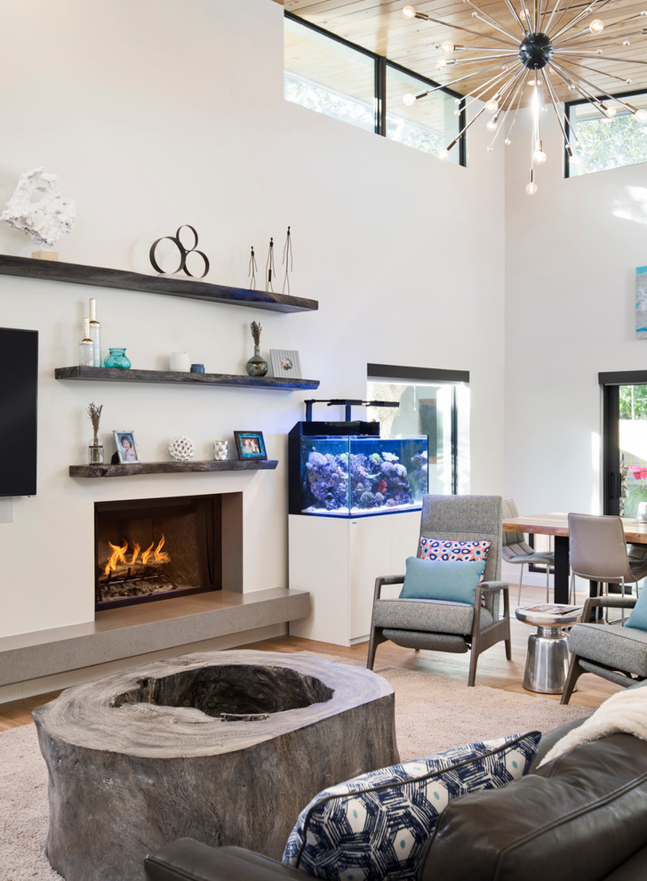 Стильный дизайн: открытая гостиная комната в современном стиле с белыми стенами, светлым паркетным полом, стандартным камином, фасадом камина из камня и телевизором на стене - последний тренд