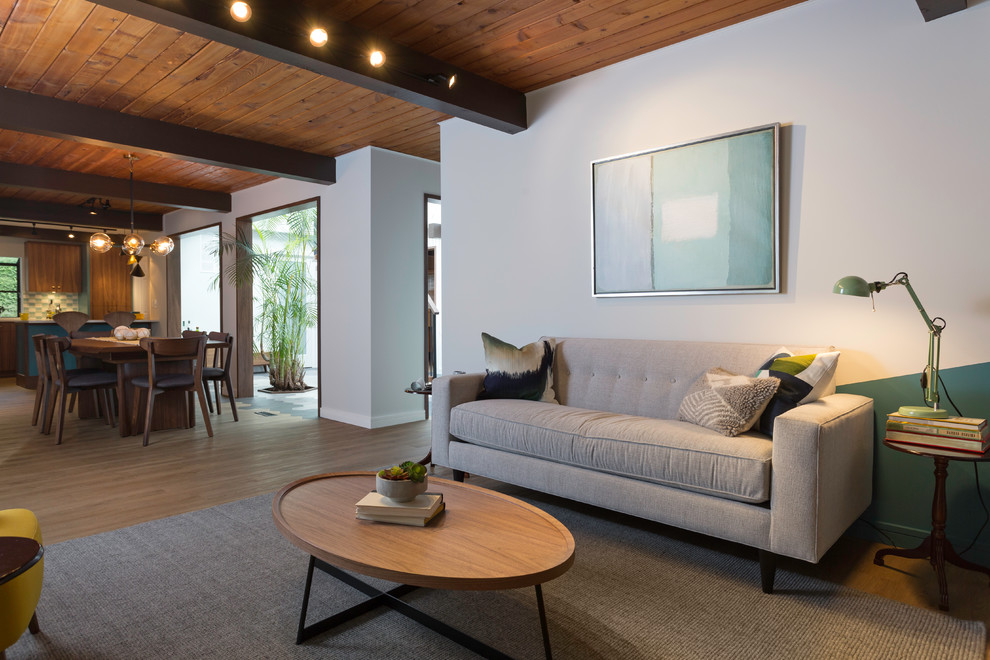 Esempio di un soggiorno moderno di medie dimensioni e aperto con pareti grigie, pavimento in legno massello medio, nessun camino, TV autoportante e pavimento marrone