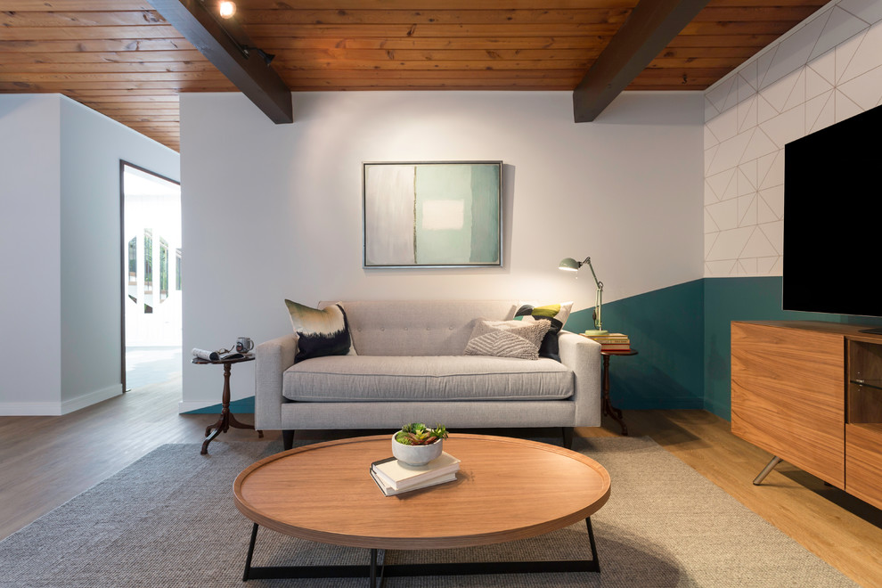 Immagine di un soggiorno moderno di medie dimensioni e aperto con pareti grigie, pavimento in legno massello medio, nessun camino, TV autoportante e pavimento marrone