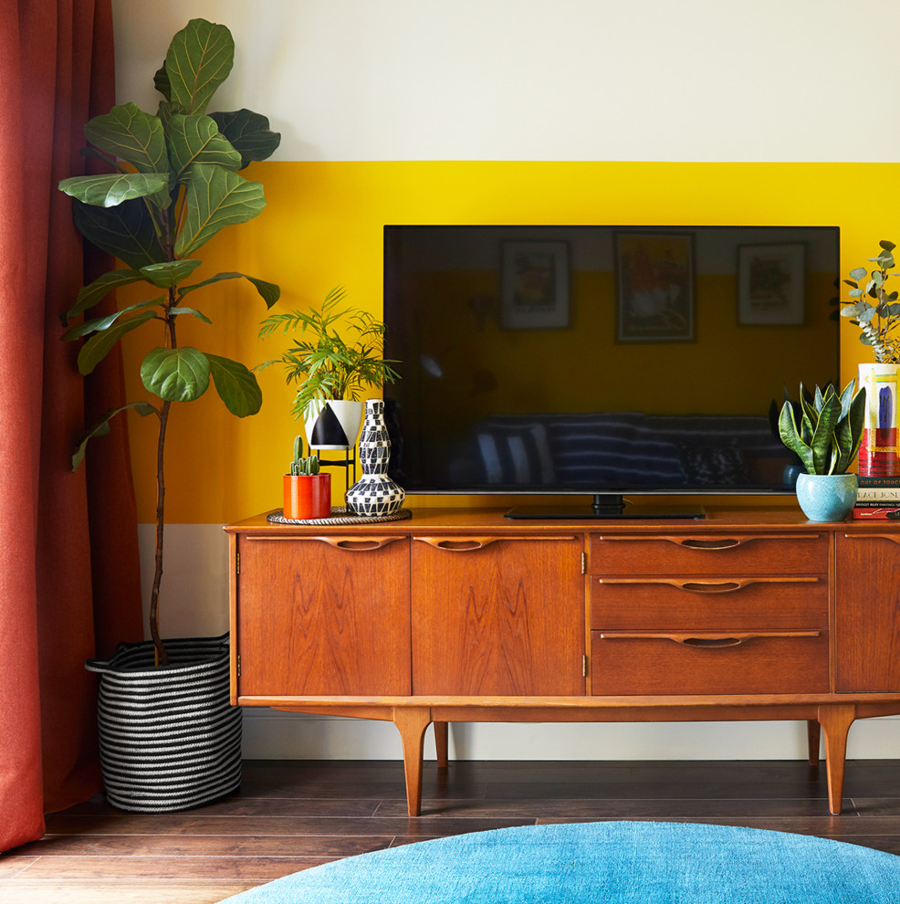 Foto på ett mellanstort eklektiskt separat vardagsrum, med gula väggar, mörkt trägolv och en fristående TV