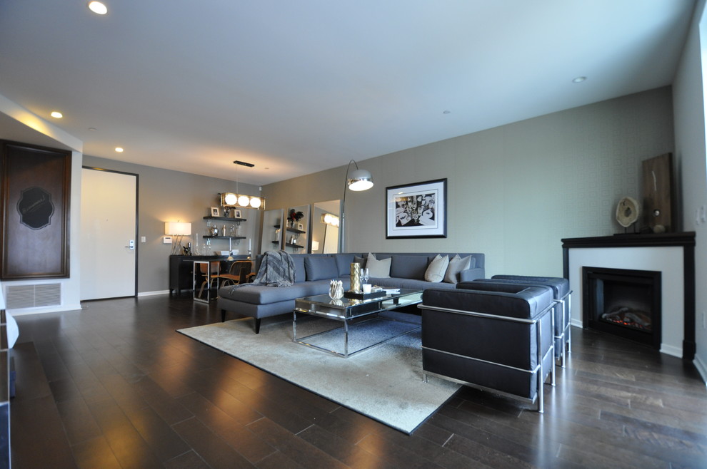 Imagen de salón abierto contemporáneo de tamaño medio con paredes grises, suelo de madera en tonos medios y chimenea de esquina