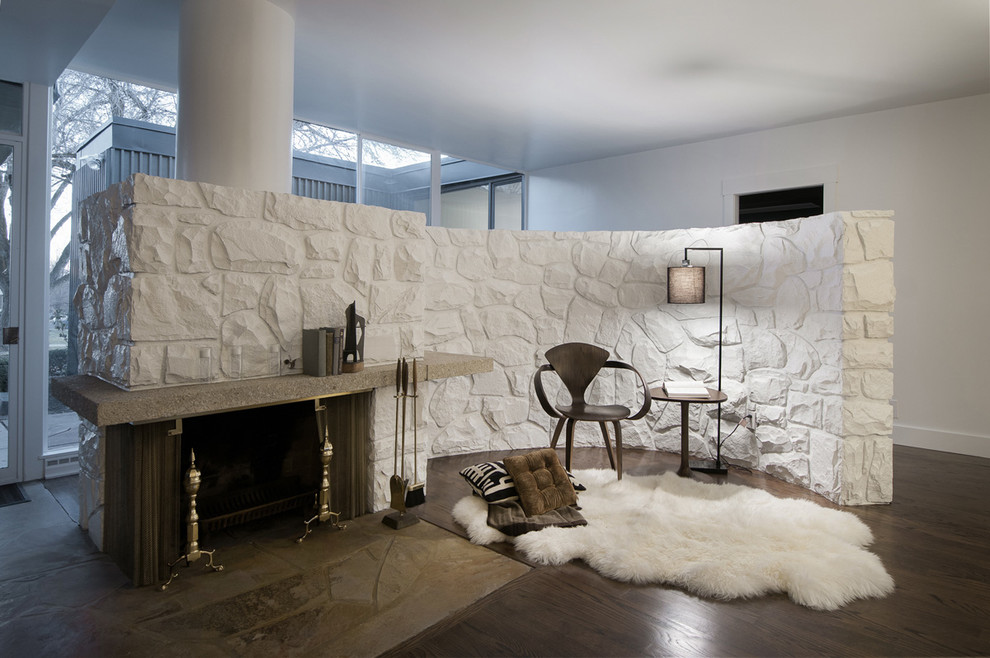 Идея дизайна: гостиная комната в стиле ретро с белыми стенами, темным паркетным полом, стандартным камином и фасадом камина из камня