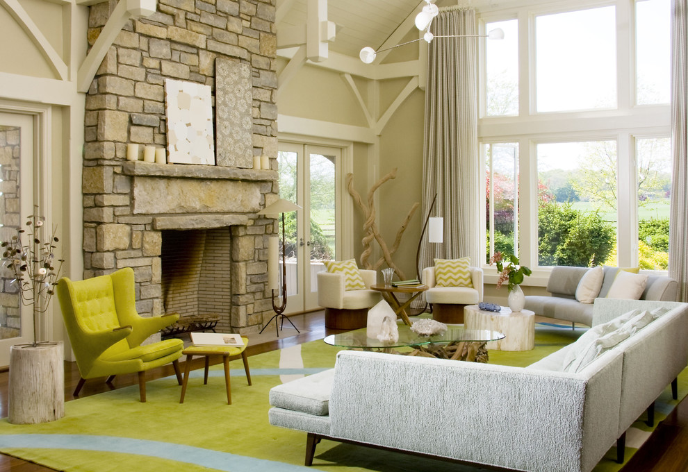 На фото: огромная гостиная комната в стиле ретро с бежевыми стенами, стандартным камином и фасадом камина из камня