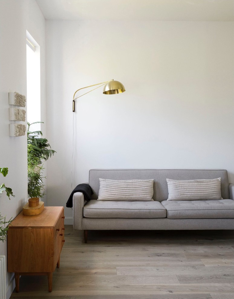 Living room - mid-century modern formal and enclosed medium tone wood floor living room idea in London with white walls, no fireplace and no tv