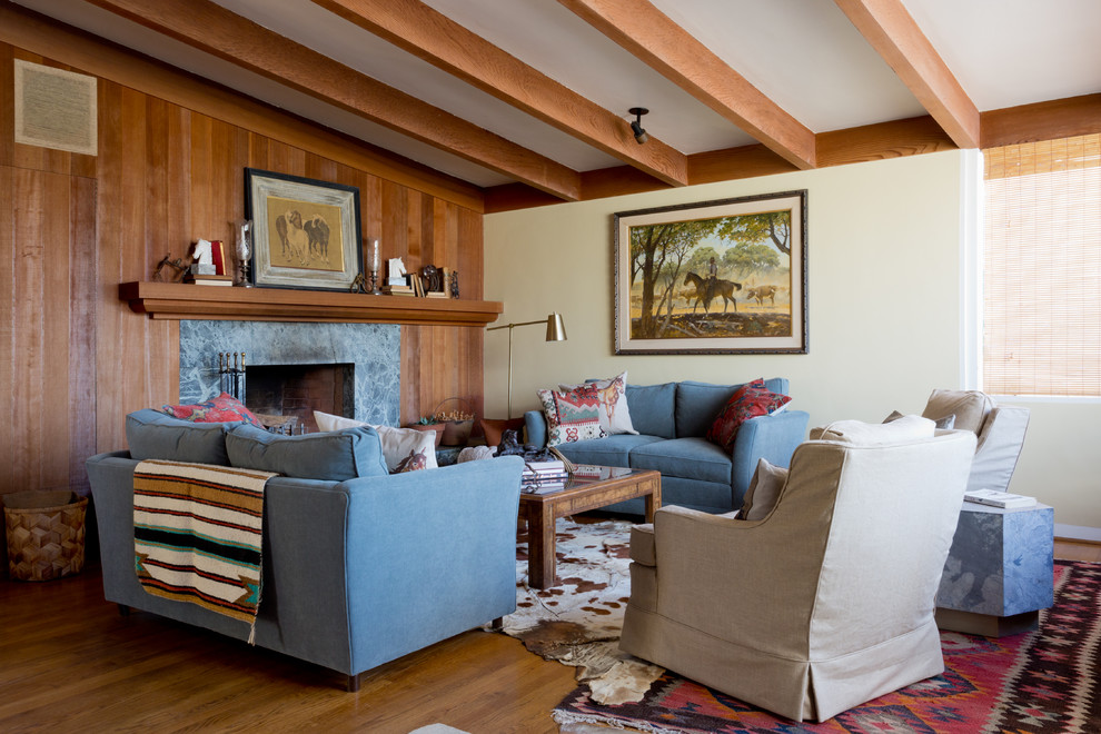 Cette photo montre un salon rétro avec un mur beige, un sol en bois brun, une cheminée standard, un manteau de cheminée en pierre et une salle de réception.