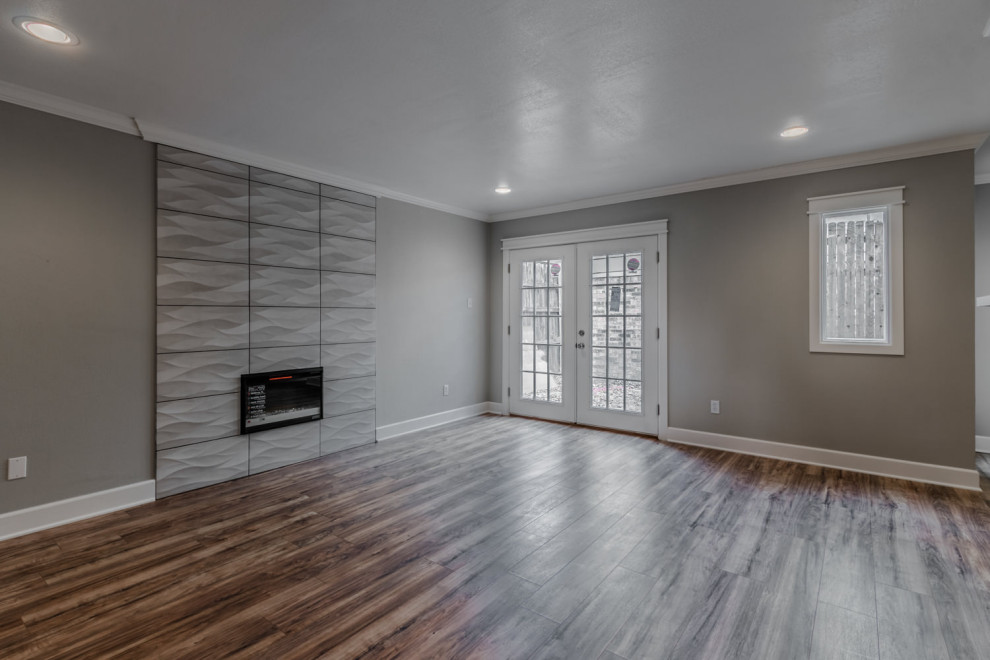 Inspiration for a mid-sized 1950s open concept laminate floor, brown floor and tray ceiling living room remodel in Dallas with gray walls, a standard fireplace and a tile fireplace