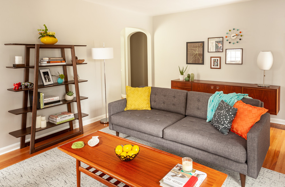 Photo of a medium sized retro enclosed living room in Detroit with grey walls, medium hardwood flooring, a standard fireplace, a tiled fireplace surround, no tv and brown floors.