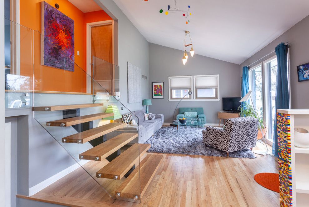 Mittelgroßes, Offenes Retro Wohnzimmer mit grauer Wandfarbe, hellem Holzboden und freistehendem TV