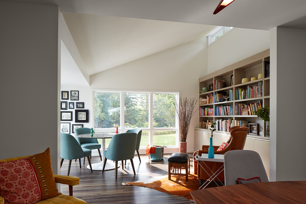 Exemple d'un salon tendance de taille moyenne et ouvert avec un mur blanc, parquet foncé, une bibliothèque ou un coin lecture et aucune cheminée.