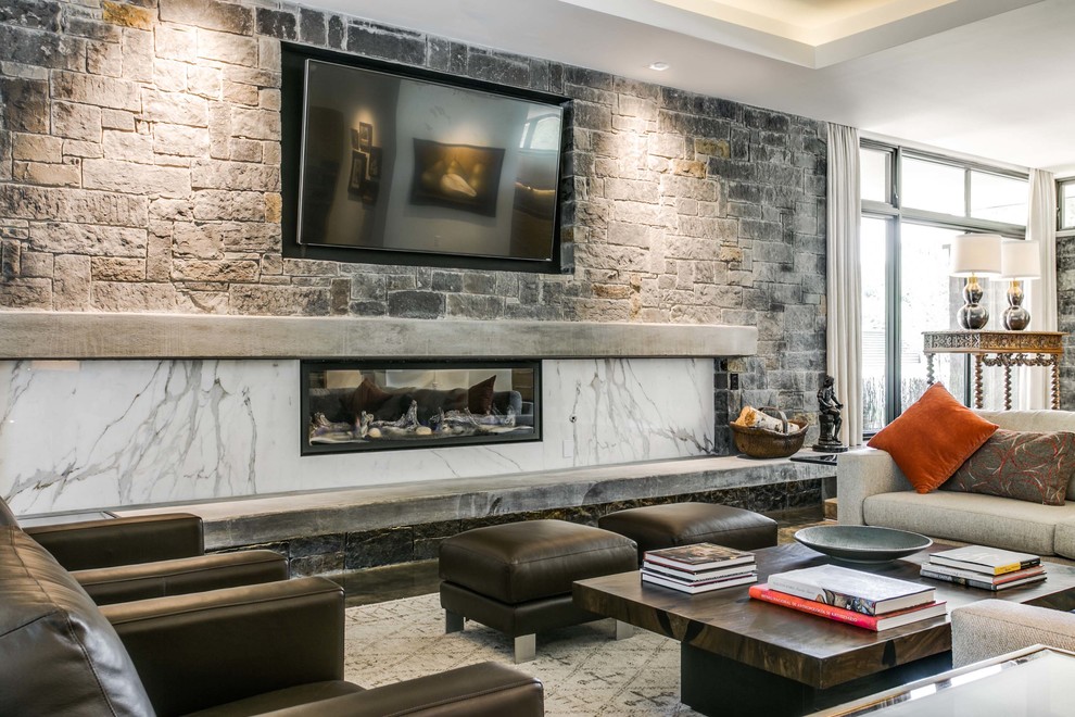 ダラスにある高級な広いミッドセンチュリースタイルのおしゃれなリビング (グレーの壁、コンクリートの床、横長型暖炉、石材の暖炉まわり、壁掛け型テレビ) の写真