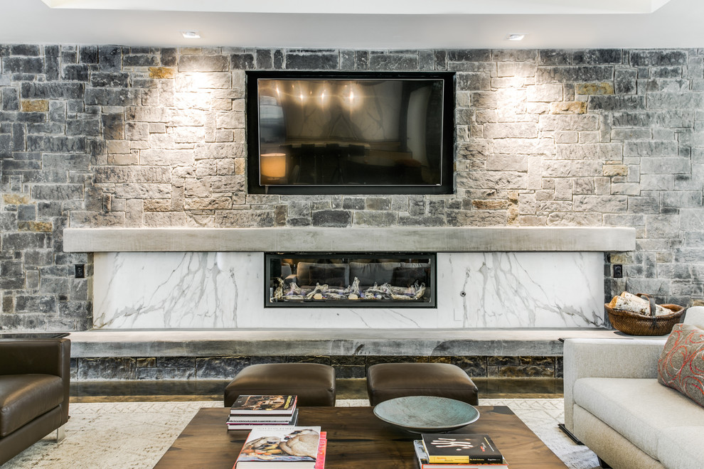 ダラスにある高級な広いミッドセンチュリースタイルのおしゃれなリビング (グレーの壁、コンクリートの床、横長型暖炉、石材の暖炉まわり、壁掛け型テレビ) の写真