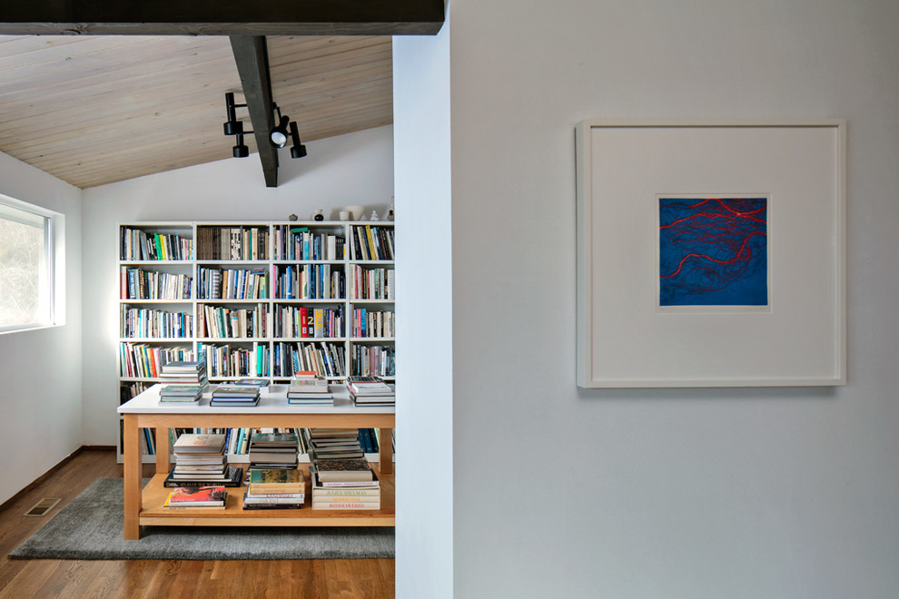 Foto på ett litet 50 tals allrum med öppen planlösning, med ett bibliotek, vita väggar, mellanmörkt trägolv och brunt golv