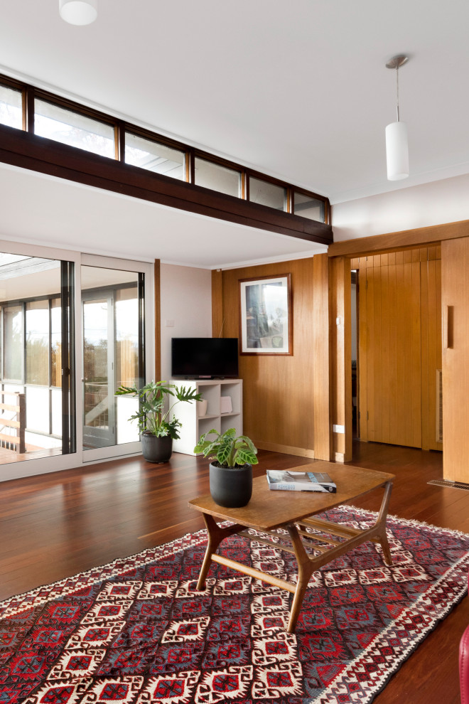 Стильный дизайн: открытая гостиная комната среднего размера в стиле ретро с белыми стенами, темным паркетным полом и коричневым полом - последний тренд
