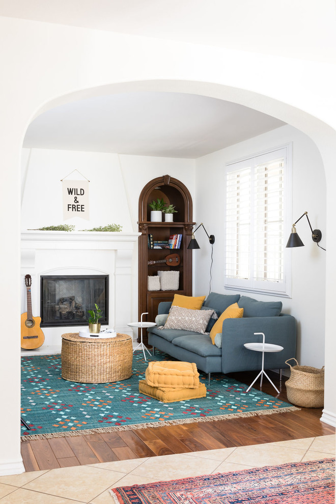 На фото: гостиная комната в стиле неоклассика (современная классика) с белыми стенами, паркетным полом среднего тона, стандартным камином, коричневым полом и синим диваном с