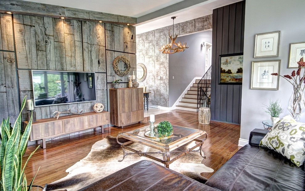 Foto de salón para visitas abierto bohemio grande con paredes grises, suelo de madera en tonos medios y televisor colgado en la pared