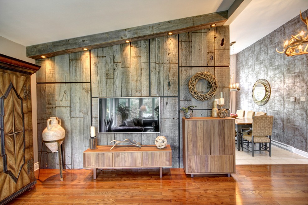 Immagine di un grande soggiorno bohémian aperto con sala formale, pareti grigie, pavimento in legno massello medio e TV a parete