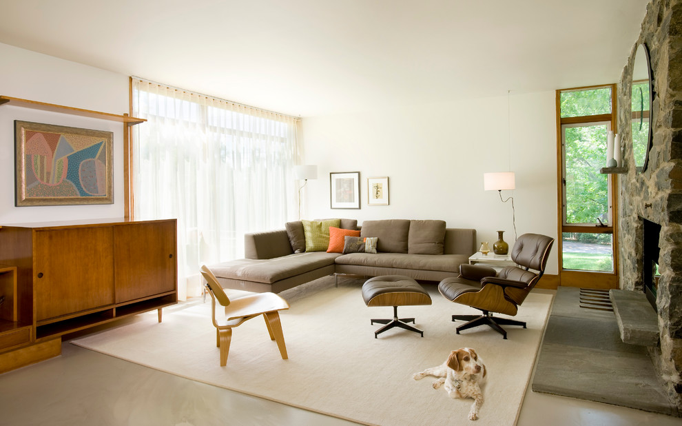 Пример оригинального дизайна: открытая гостиная комната среднего размера в современном стиле с белыми стенами, бетонным полом, фасадом камина из камня, скрытым телевизором, серым полом и коричневым диваном