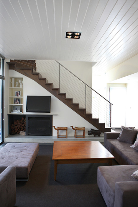 Ejemplo de salón cerrado minimalista de tamaño medio con paredes blancas, suelo de pizarra, estufa de leña, marco de chimenea de metal y televisor colgado en la pared