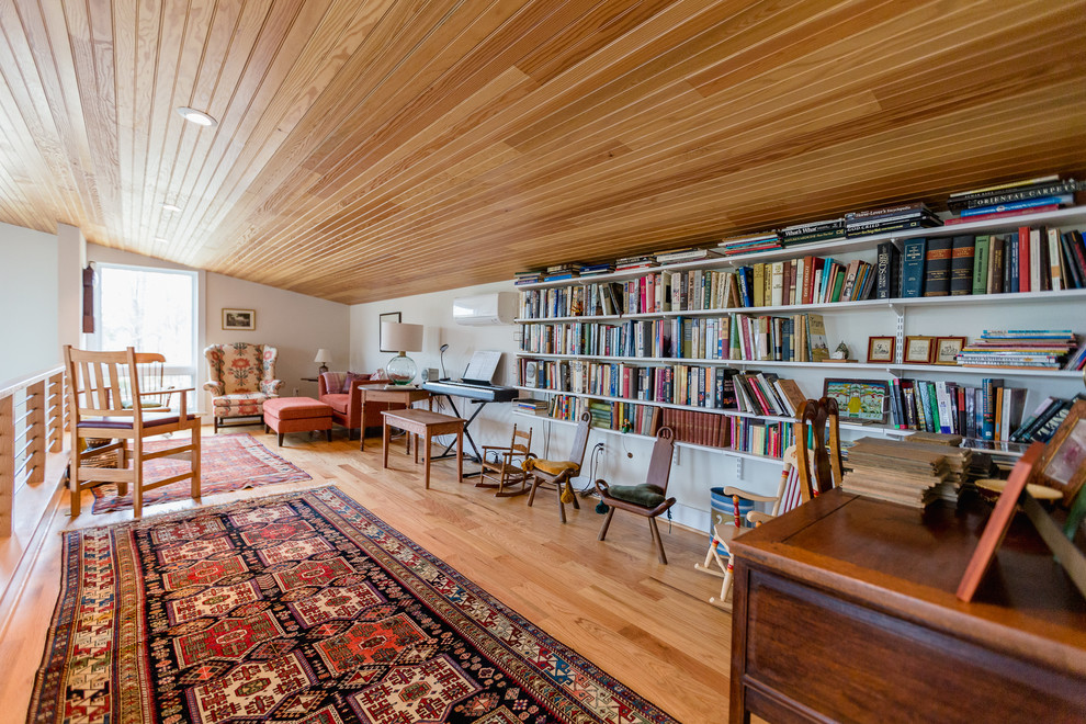 Foto di un soggiorno country di medie dimensioni e stile loft con libreria, pareti bianche, parquet chiaro, nessun camino e pavimento marrone