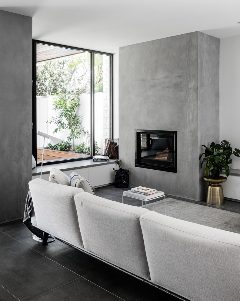 Contemporary living room in Melbourne with a standard fireplace, a concrete fireplace surround and black floors.